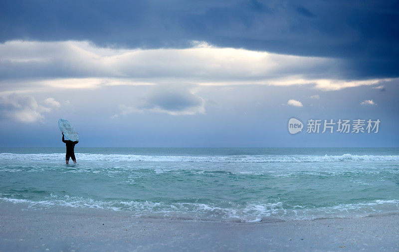 年轻人携带冲浪板和暴风雨的海景