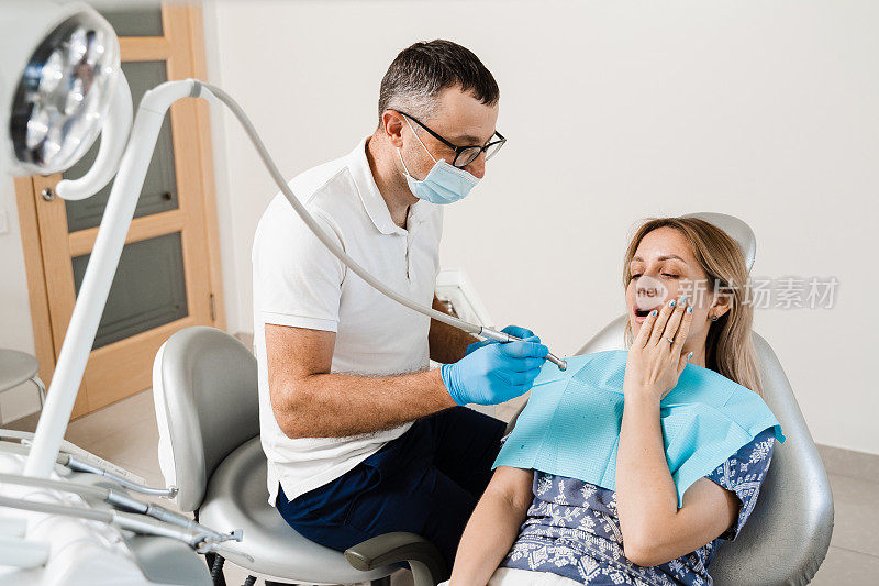 迷人的女人害怕牙医。牙医向受惊的女孩咨询牙科。牙科中牙齿和牙痛的治疗。