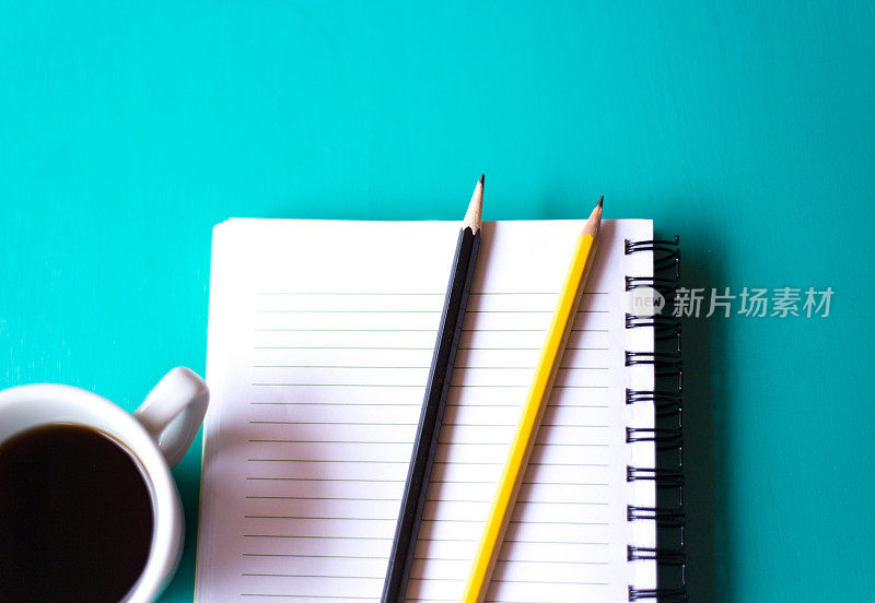 准备工作:笔记本，咖啡，两支铅笔，蓝绿色背景