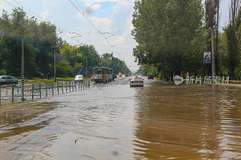 洪水。水下的道路和汽车。暴雨淹没了城市街道。强大的泛滥。自然异常。坏天气。灾难。汽车和公共交通陷入困境。自然