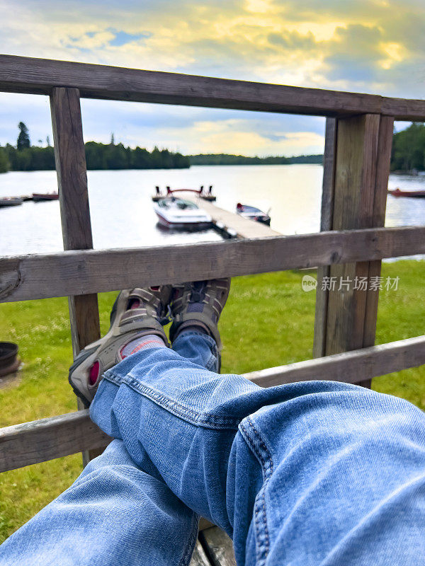第一人称视角:在远处有湖和船坞的甲板上放松。一天结束时，一只面目全非的雄性正在休息