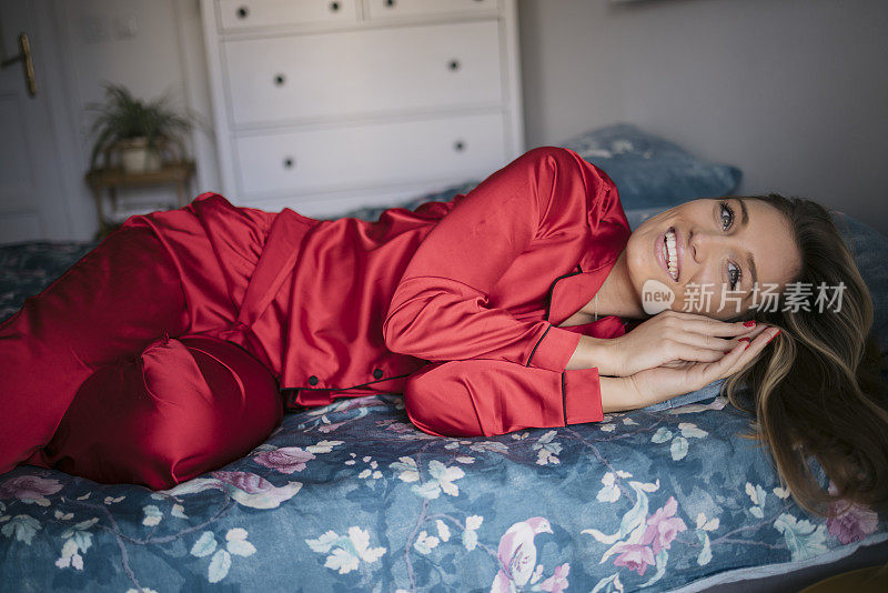穿着红色睡衣的微笑白人女性躺在床上