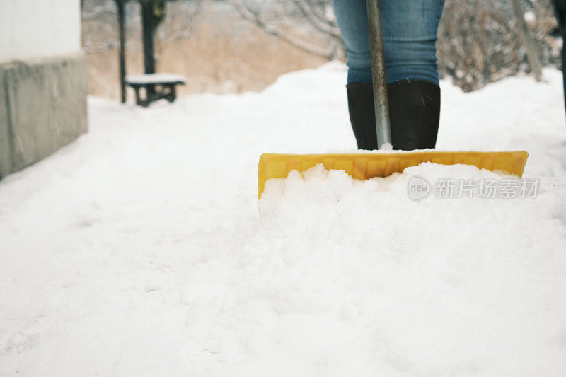 一个女人正在前院铲雪