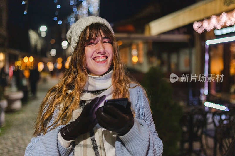 漂亮女孩晚上在城里用她的智能手机