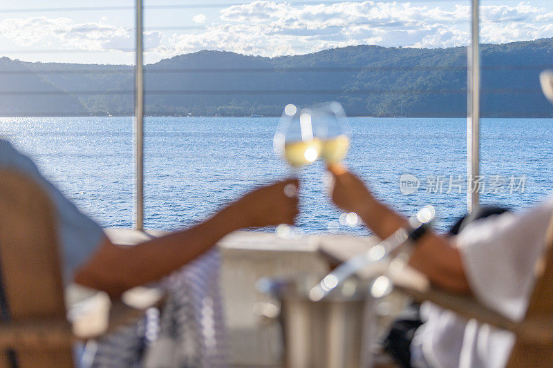 一对夫妇在水上平房的躺椅上放松和喝葡萄酒。