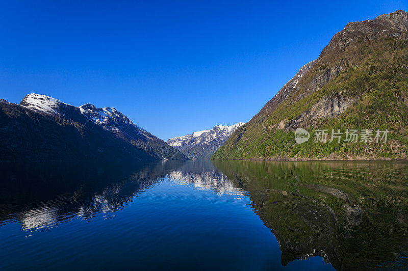 从Geirangerfjord乘船欣赏雪山、树木、瀑布和晴朗的天空