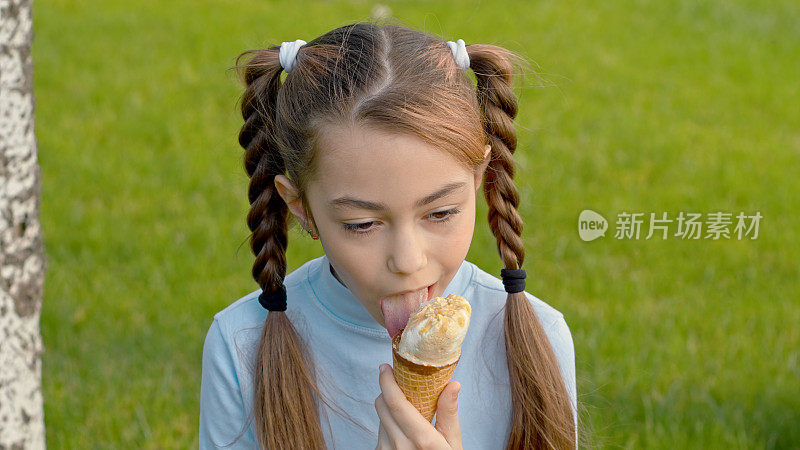 小女孩正高兴地舔着冰淇淋蛋筒，她的脸上露出满意的神情