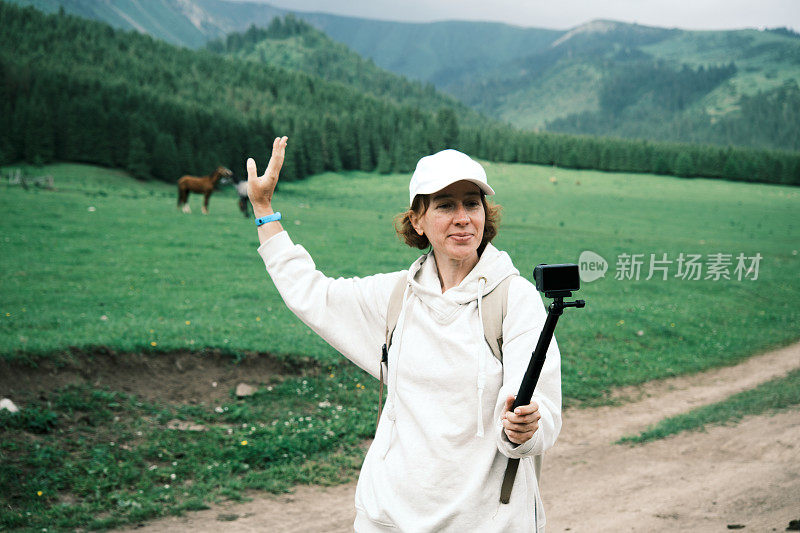 女游客在美丽的山谷中与吃草的马一起展示自己