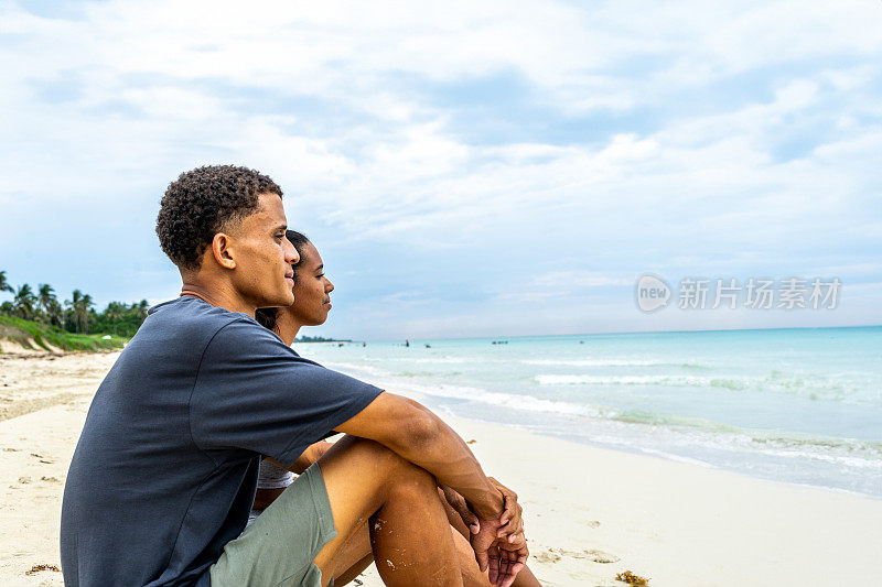 年轻夫妇坐在海边望向远方