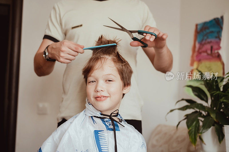 在隔离条件下的美发沙龙。父亲用剪刀给儿子剪头发。男人在家里给男孩理发。经济危机中的经济概念。