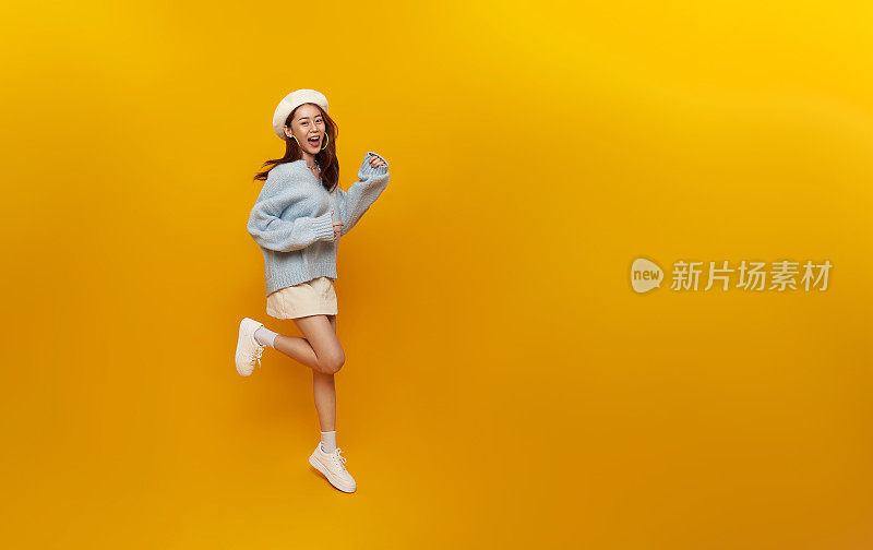 全长快乐美丽的亚洲少女在黄色工作室背景上跳跃。本空间