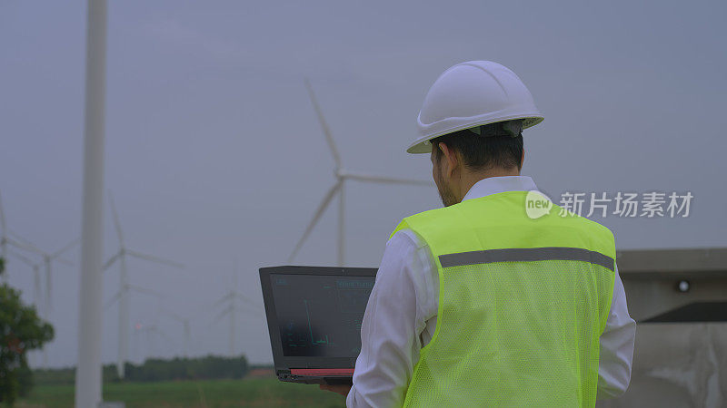 一名工程师在风力涡轮机农场用笔记本电脑分析和开发风力发电