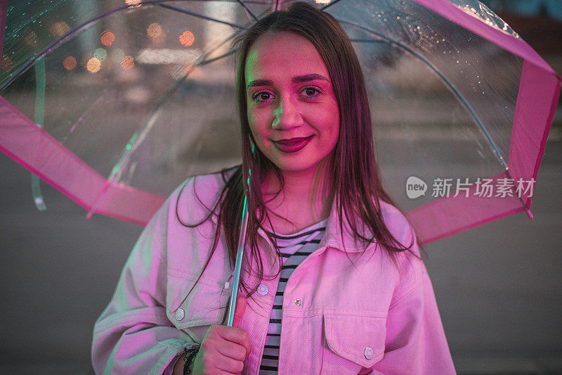 一个无忧无虑的女人在雨夜撑伞散步的肖像