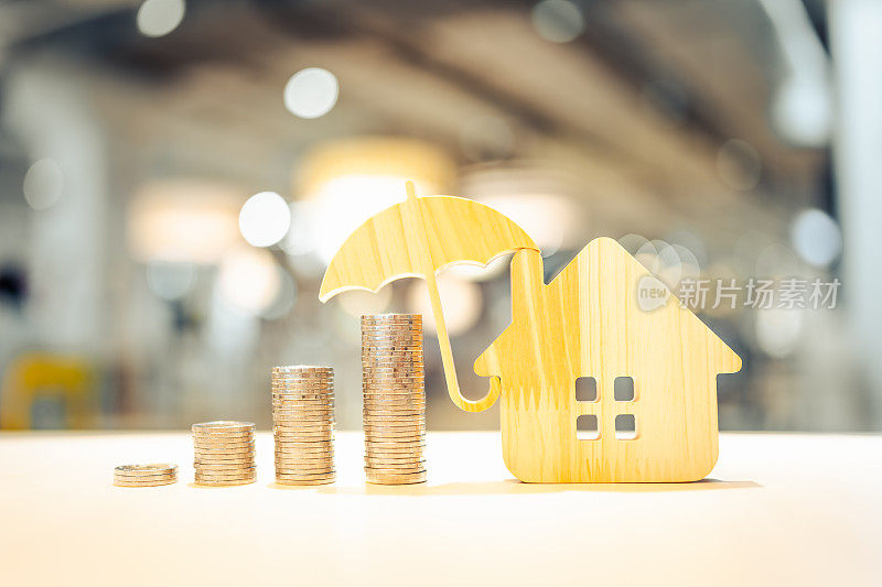 模型伞用房子和木桌上的硬币概念的保险制度，节省了健康保险的费用