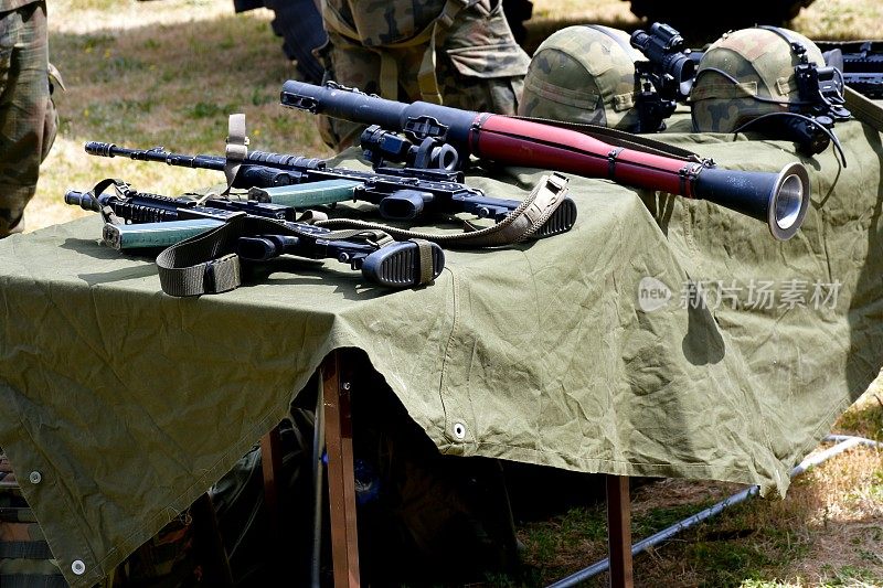 在夏季组织的一次军事野餐中，在一张铺着布的小桌子上展示的现代武器，包括机枪、头盔、瞄准镜、导弹发射器和火箭筒