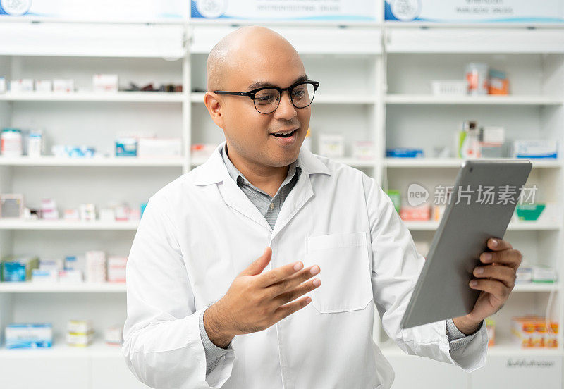 穿着制服的专业药剂师拿着药瓶，通过在线视频会议向站在药品货架柜台附近的顾客提供建议。药剂师库存药