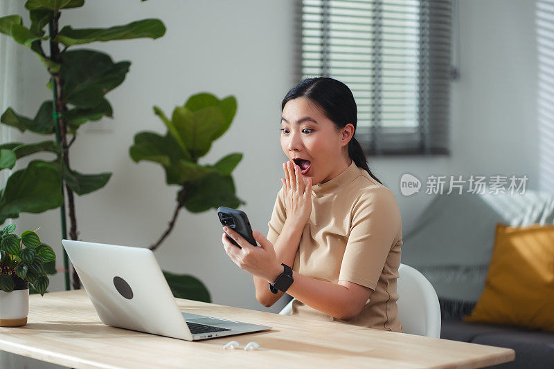 亚洲女性坐在家里用智能手机开心兴奋。