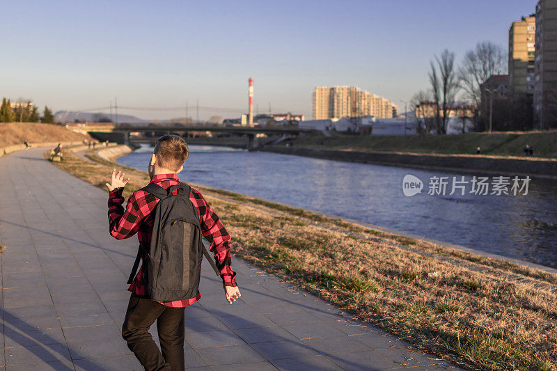 日落时分，可爱的男孩在河边散步。