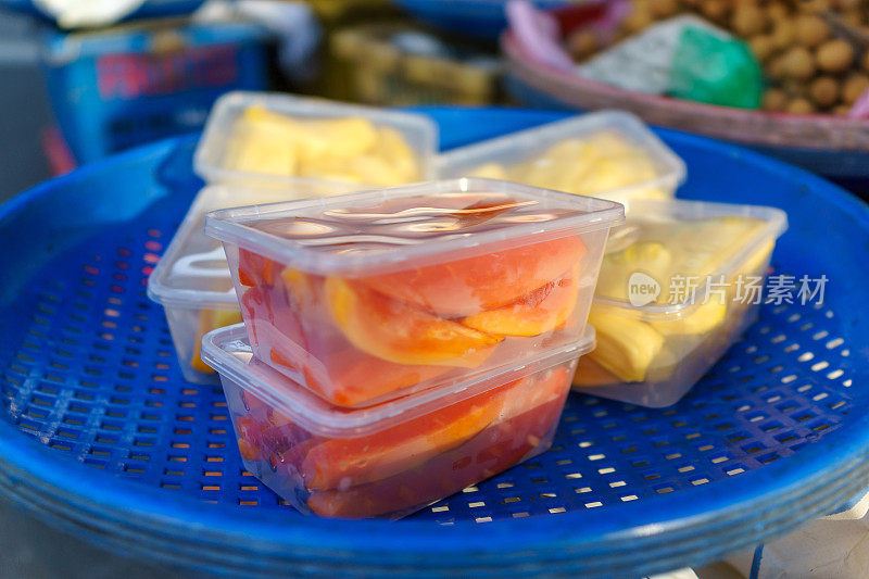 木瓜和菠萝蜜被放在一个外带塑料盒里，准备在市场摊位上出售