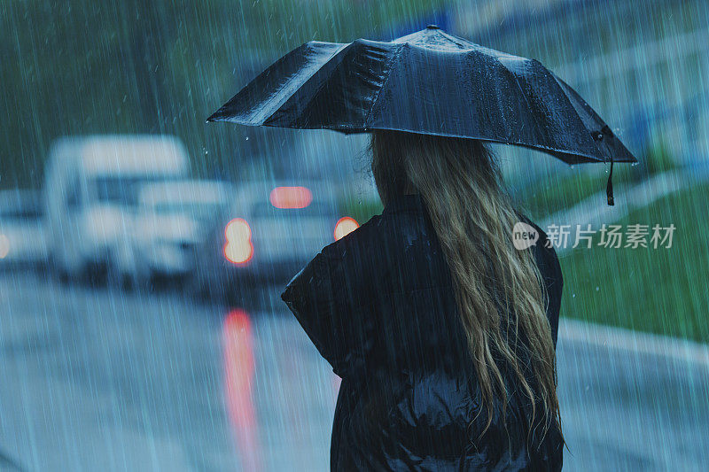 伞下的金发女人。暴风雨天气。暴雨