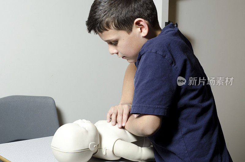 一个小男孩在玩偶上练习心肺复苏