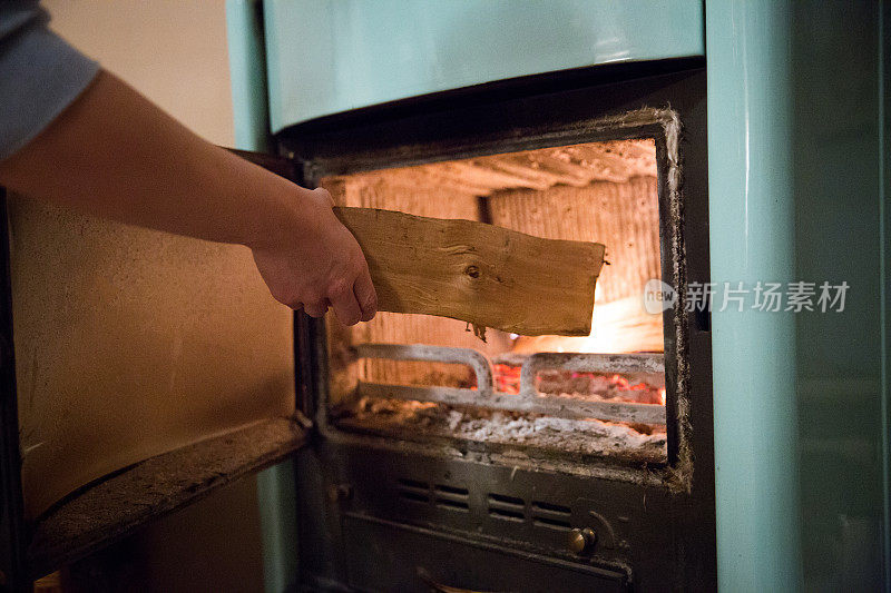 女人把木头放在烧木头的炉子上