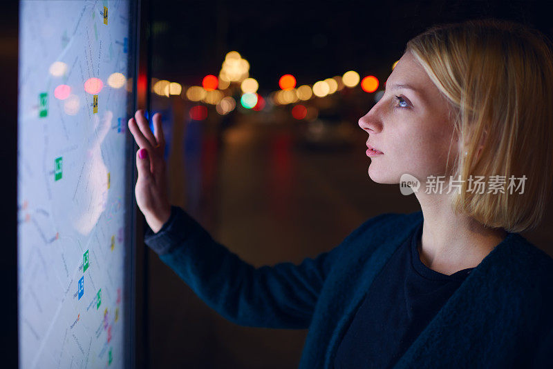 一个女人站在大屏幕前，上面有基本的城市地图