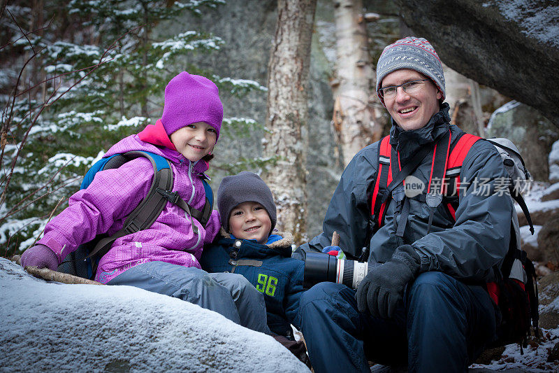 快乐的家庭在冬天的森林徒步旅行