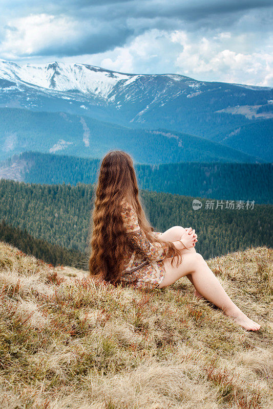 年轻女子坐在山的山坡上