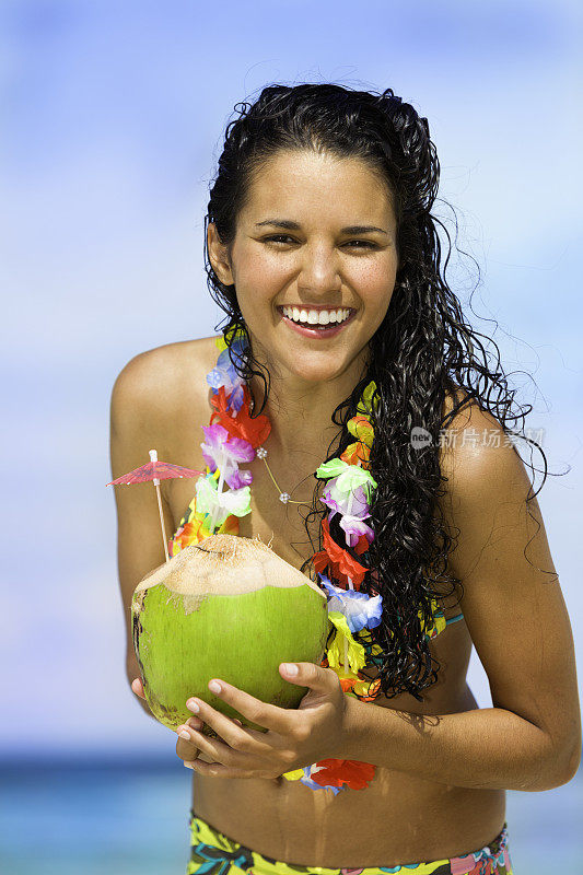 快乐的年轻女子与椰子汁在热带绿松石海滩