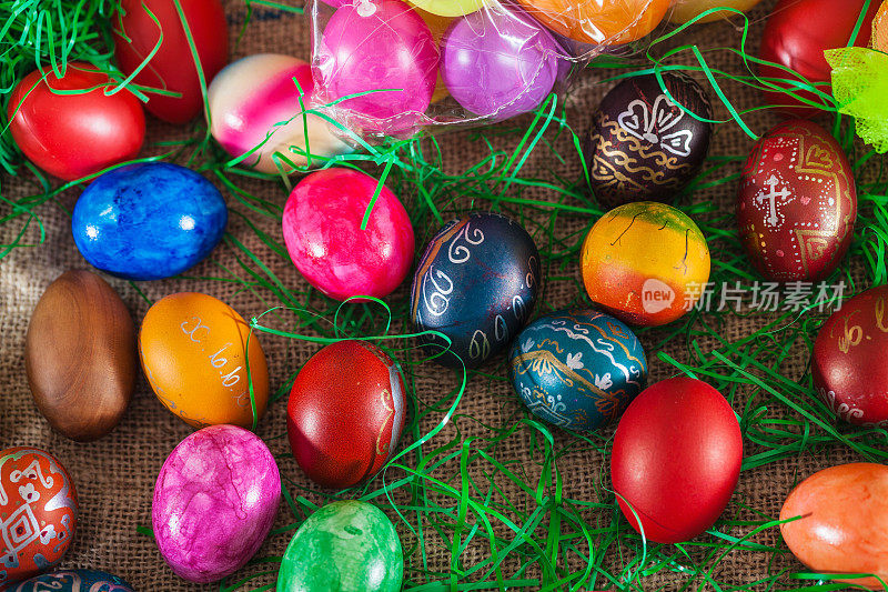 五颜六色的复活节彩蛋和旧皱布上的人造草