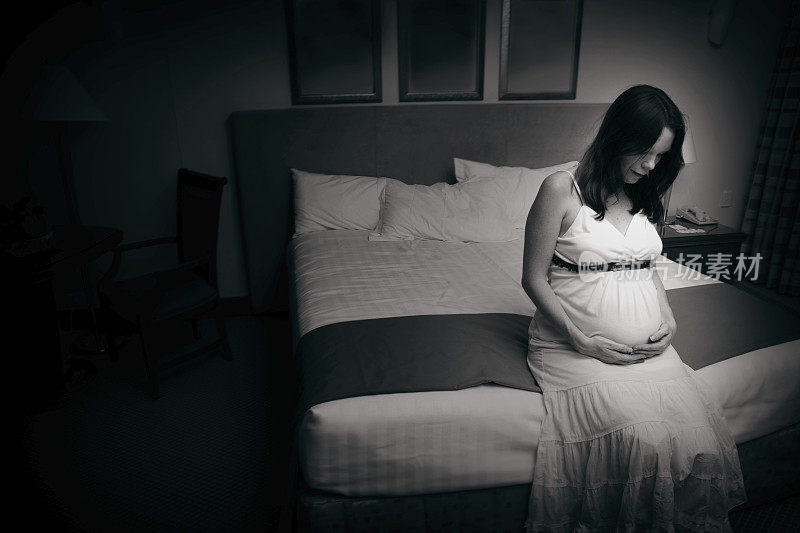 一张孕妇坐在床上的黑白照片