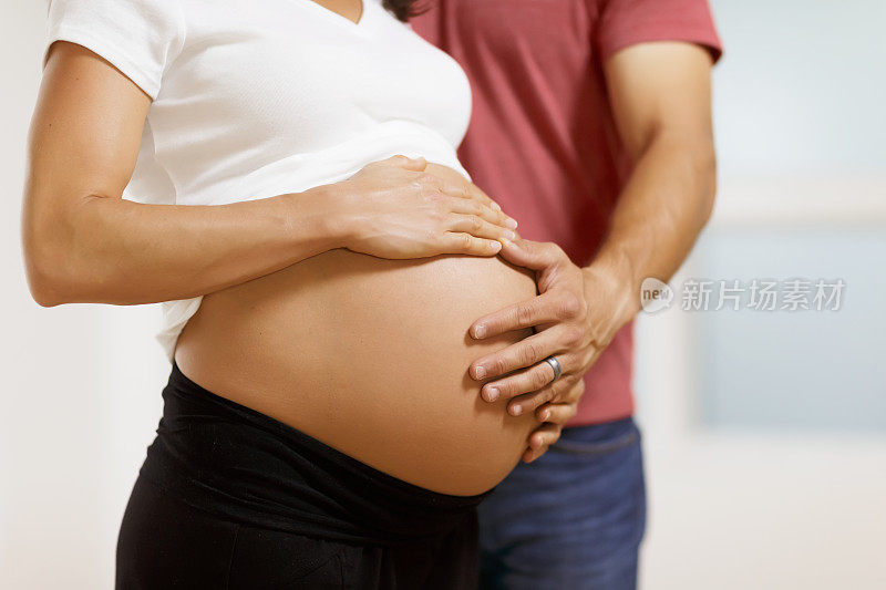 孕妇向丈夫展示裸露的腹部。