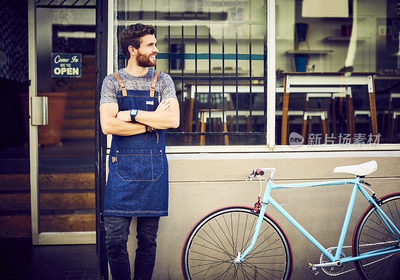 咖啡师双手交叉在咖啡馆外的自行车旁