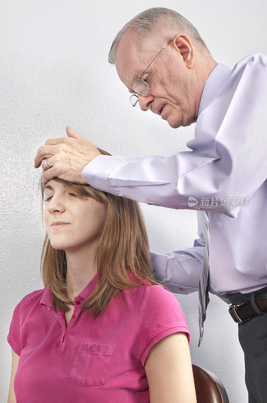 女病人的脊椎检查，捏脊医生稳住她的前额