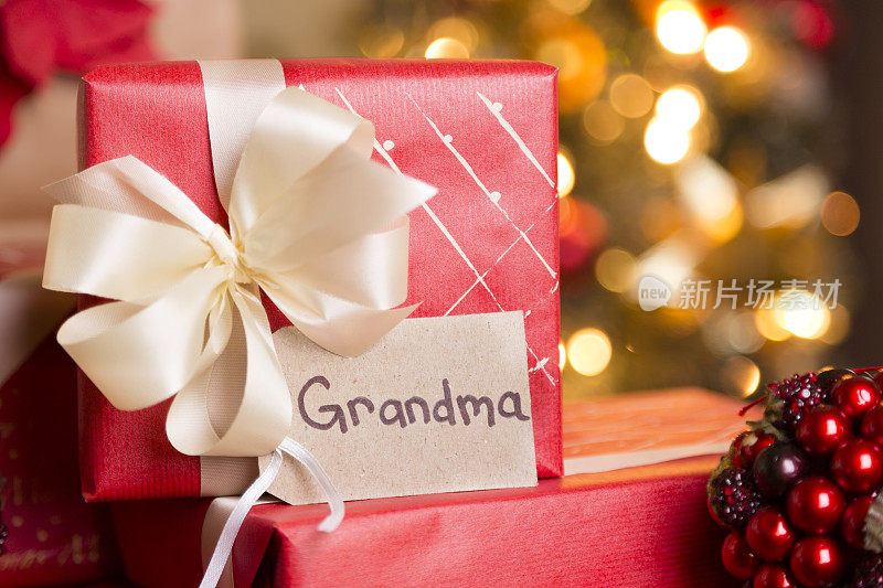 圣诞节:给奶奶包装精美的节日礼物。树在后台。