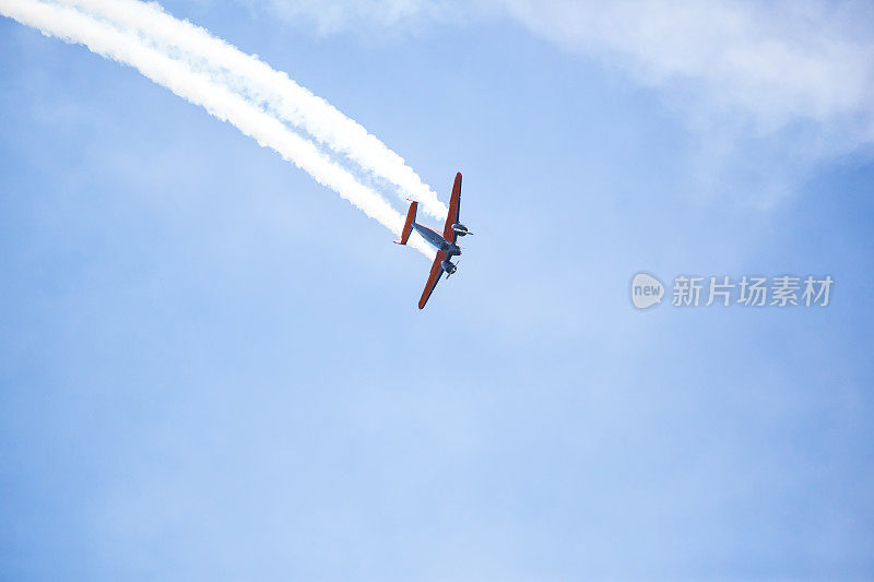 飞机拖着缕缕烟雾在空中翱翔