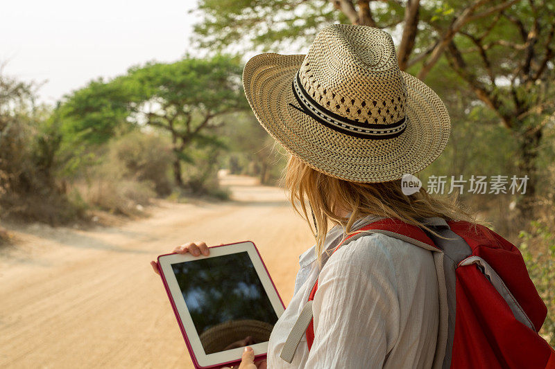 在沙漠路上用平板电脑的女人