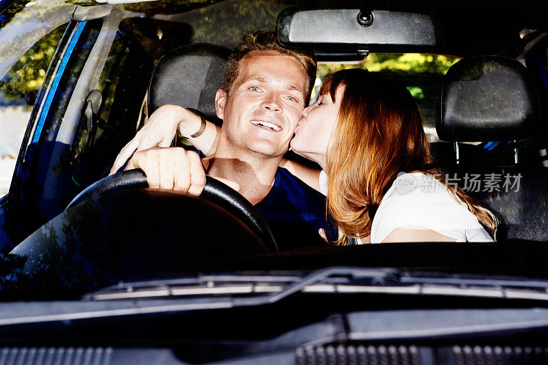 年轻女子冲动地亲吻开车的男友。有趣,但是危险!