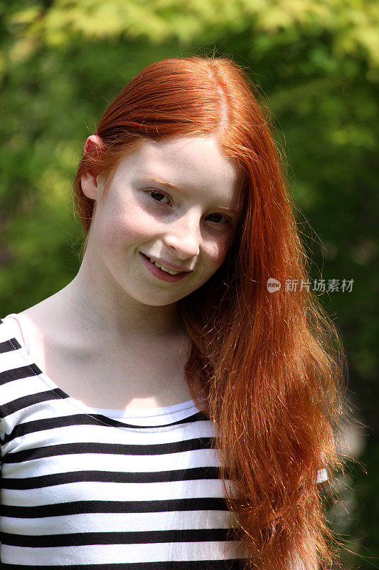 在阳光下，一头红长发的女孩