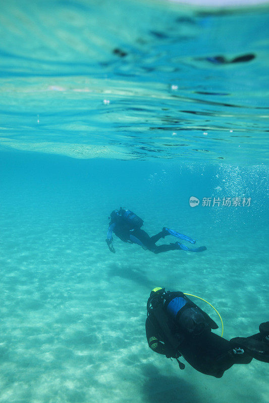 两名潜水员在蓝色泻湖中潜水