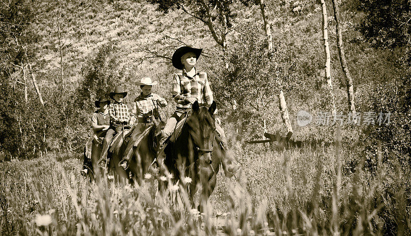 狂野西部的女人带领着她的家人骑在马背上