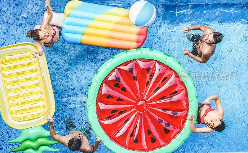 快乐的朋友在游泳池里玩球-年轻人在暑假度假-旅游，假期，青年，友谊和热带概念-季节性色彩色调过滤