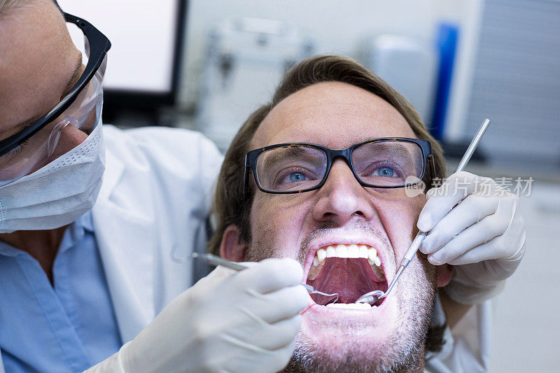 女牙医用工具检查男性病人