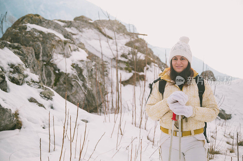 女人拿着滑雪板，背景是高山