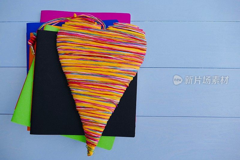 彩色的笔记本和一个彩色的心躺在上面
