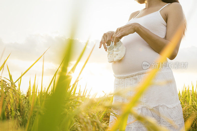 稻田里一个孕妇穿着婴儿拖鞋