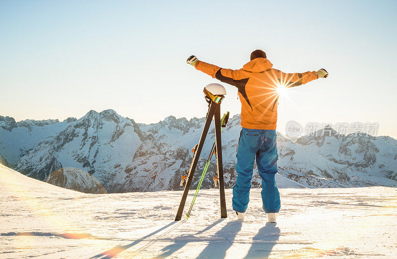 年轻的专业滑雪者在日落在法国阿尔卑斯山滑雪胜地放松的时刻-冬季运动概念与冒险的家伙在山顶准备骑下来-背光的观点与明亮温暖的滤镜