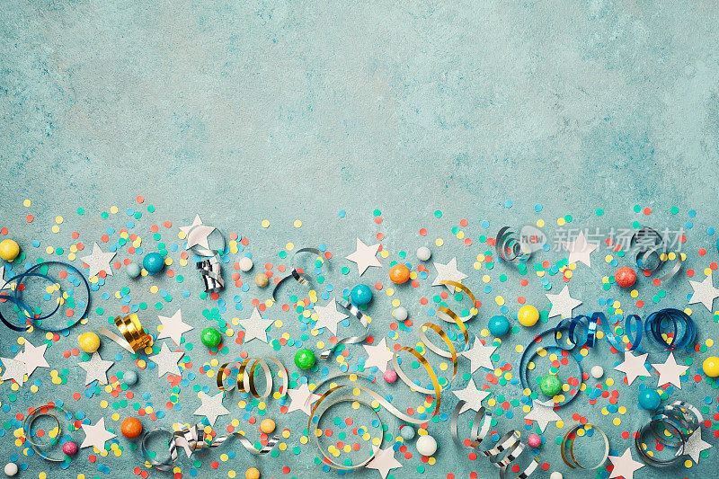 假日背景装饰彩色的五彩纸屑，星星，糖果和流光在蓝色复古桌顶视图。平的风格。