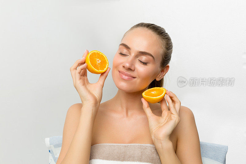 美丽的年轻女子拥有完美健康的皮肤，拿着橙色